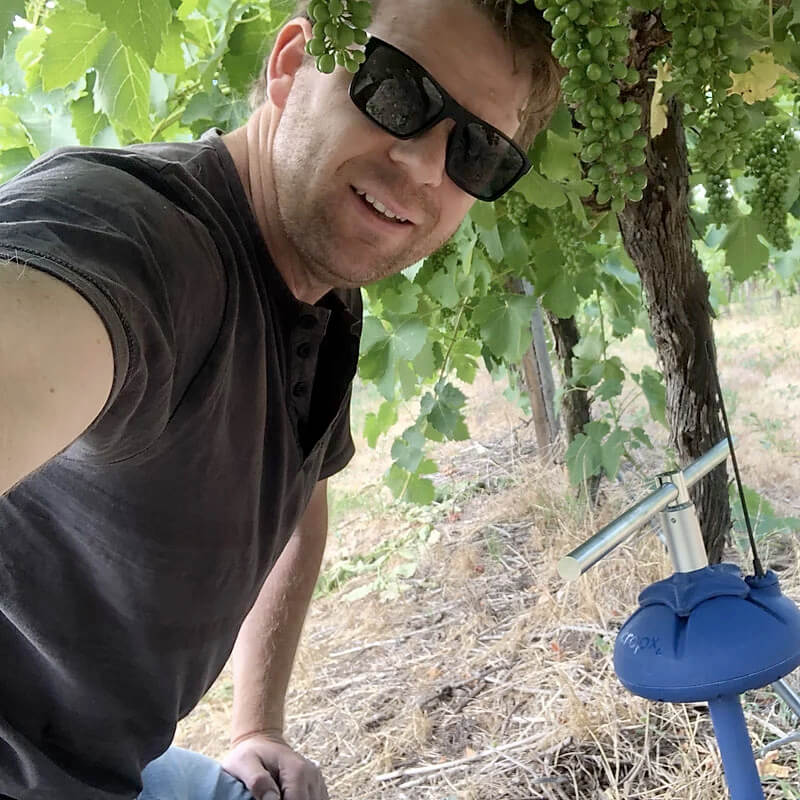 Alex smiling with irrigation system - smart irrigation for sustainable wine